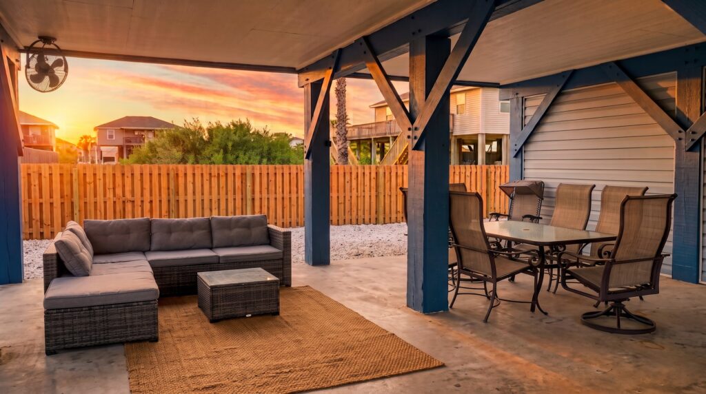 Covered patio with lounge seating and dining in the fenced backyard